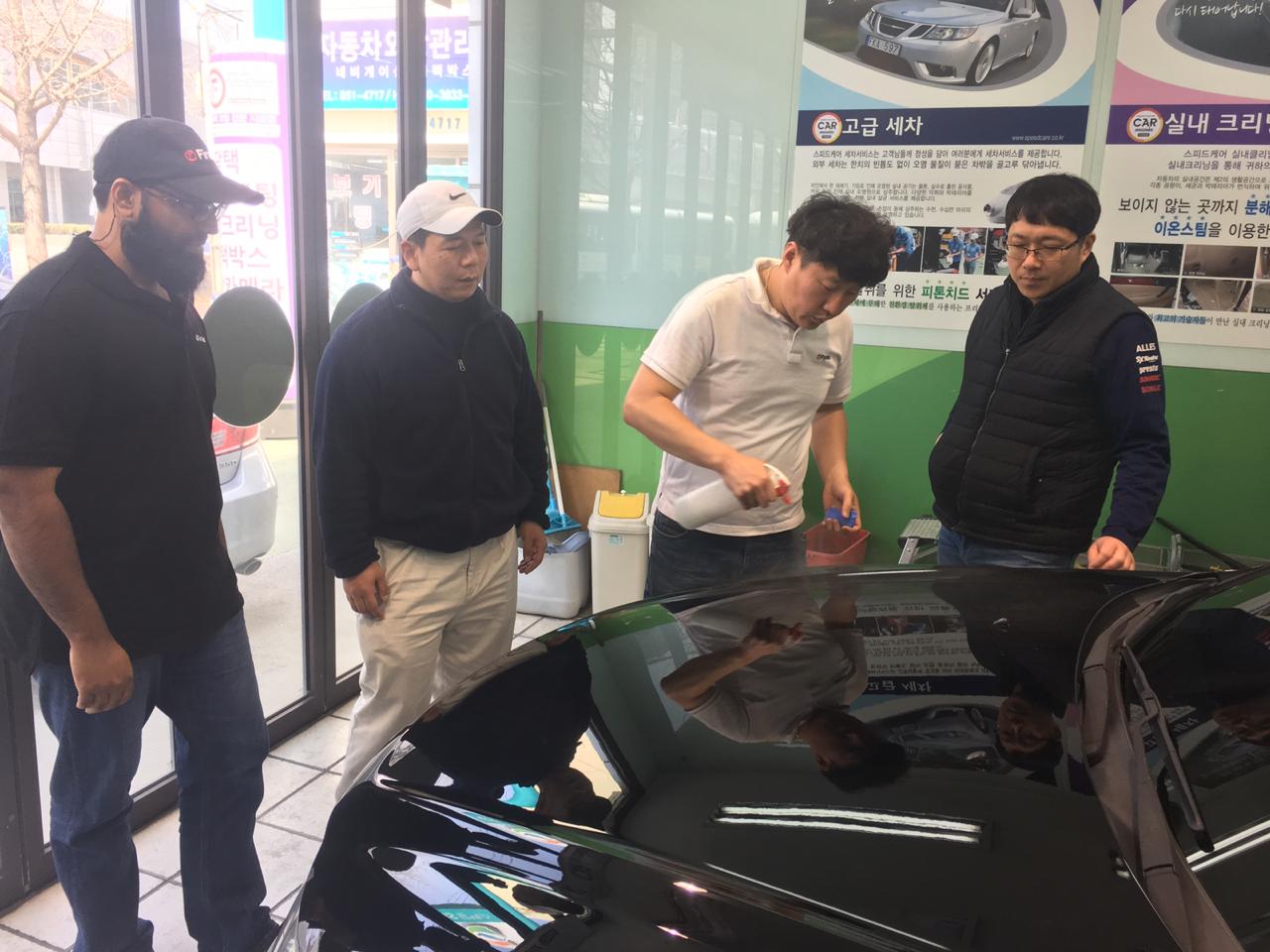 Our Legacy of Excellence in Auto Care Participants observing a detailing demonstration on a black vehicle during training in Busan